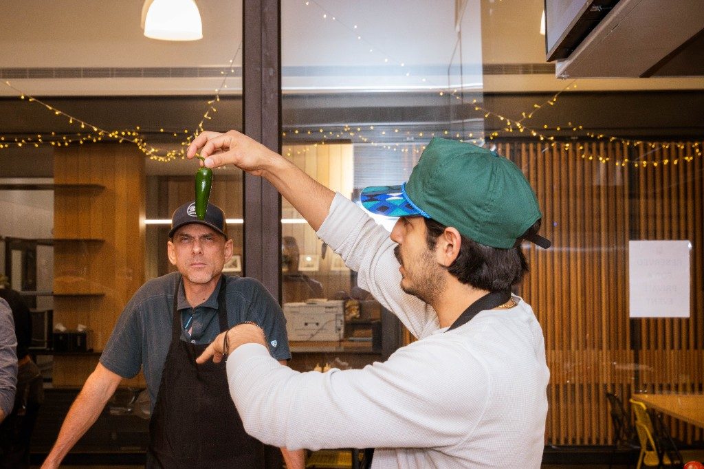 A chef holding up a jalapeño during a class demonstration